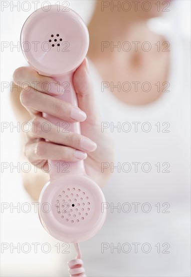 USA, New Jersey, Jersey City, Woman's hand holding pink telephone receiver. Photo : Jamie Grill Photography