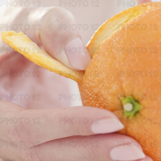 USA, New Jersey, Jersey City, Close-up view of woman's hand peeling orange. Photo : Jamie Grill Photography
