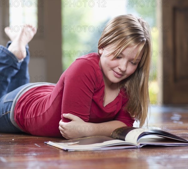 USA, Utah, Girl (10-11) reading book on floor in home. Photo : Tim Pannell