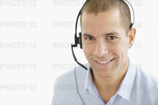 South Africa, Portrait of smiling young man wearing headset, studio shot. Photo : momentimages