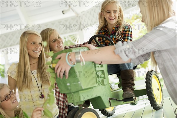 USA, Utah, family portrait of sisters (6-7, 8-9, 12-13, 14-15, 16-17) at table playing with tractor toy. Photo : Tim Pannell