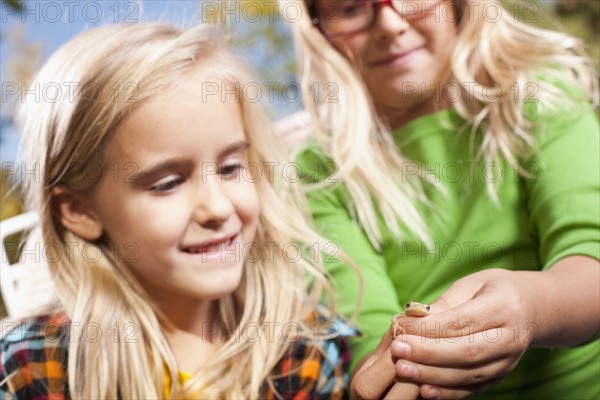 USA, Utah, close up of sisters (6-7, 8-9 ) holding frog. Photo : Tim Pannell