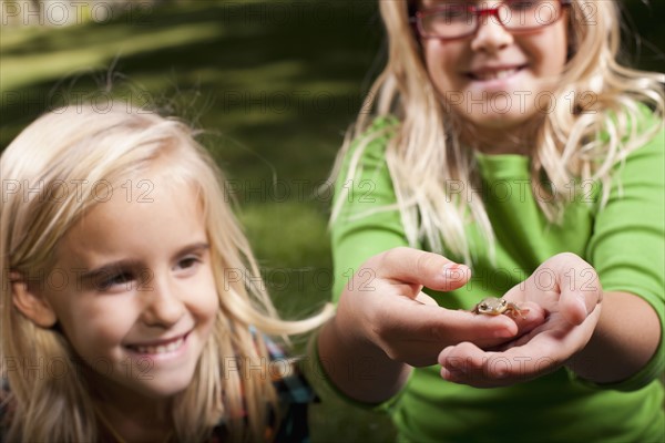 USA, Utah, close up of sisters (6-7, 8-9 ) holding frog. Photo : Tim Pannell