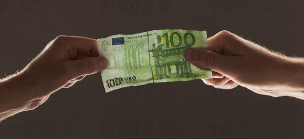 Hands holding one hundred euro note. Photo : Mike Kemp