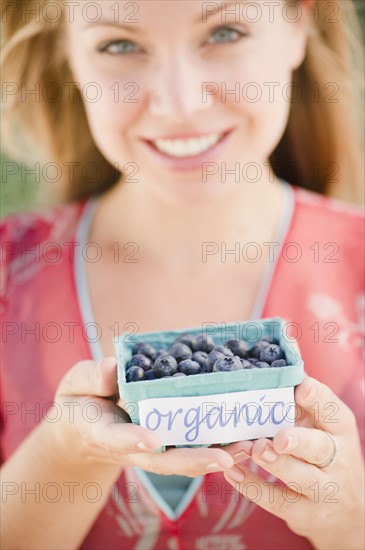 USA, New Jersey, Jersey City, Young attractive woman offering box of blueberries. Photo : Jamie Grill Photography