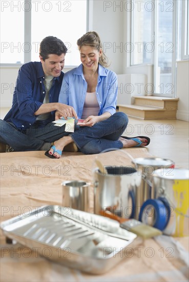 USA, New Jersey, Jersey City, Couple sitting near painting equipment in new home .