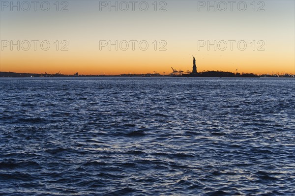 USA, New York City, Staten Island, Harbor and silhouette of Statue of Liberty in background.