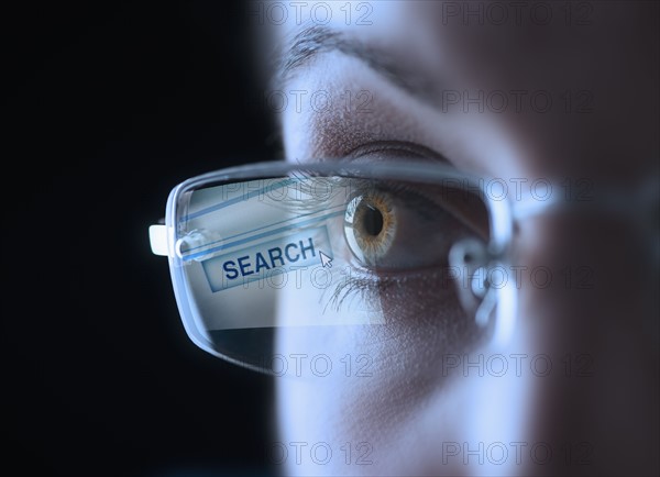 Reflection of search button in businesswoman's glasses.