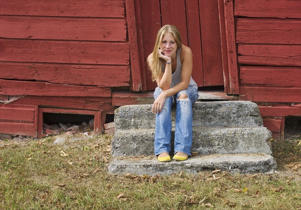 Portrait of woman sitting outside wooden house.