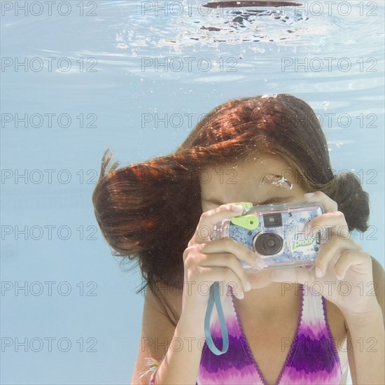 USA, New York, Girl (10-11) taking photo in swimming pool. Photo : Jamie Grill Photography