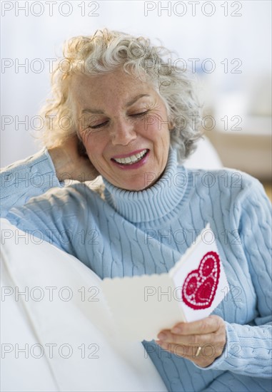 USA, New Jersey, Jersey City, Senior woman reading Valentines card in living room.