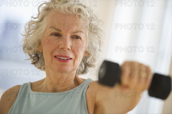 USA, New Jersey, Jersey City, Senior woman using hand weights at gym.