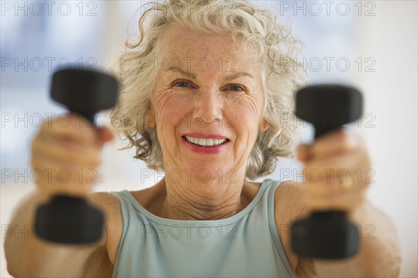 USA, New Jersey, Jersey City, Portrait of senior woman using hand weights at gym.