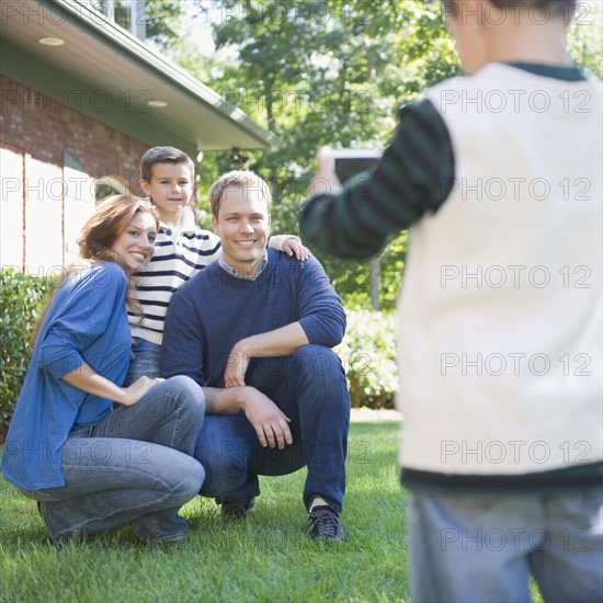 USA, New York, Flanders, Boy (4-5) taking photograph of mother, father and brother (8-9). Photo : Jamie Grill Photography