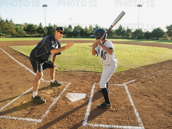 Baseball coach and boy (10-11) standing on baseball diamond.