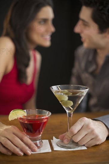 Young couple having drinks and flirting, studio shot.