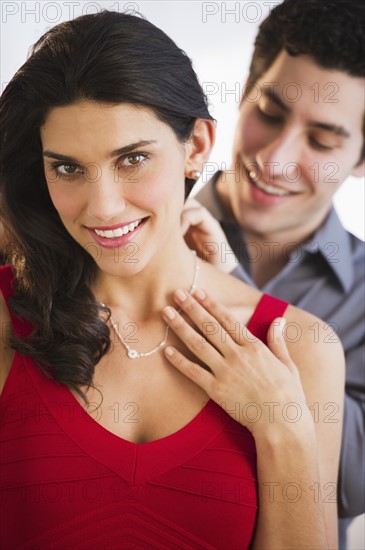 Young couple, man fastening woman's necklace. Photo : Daniel Grill