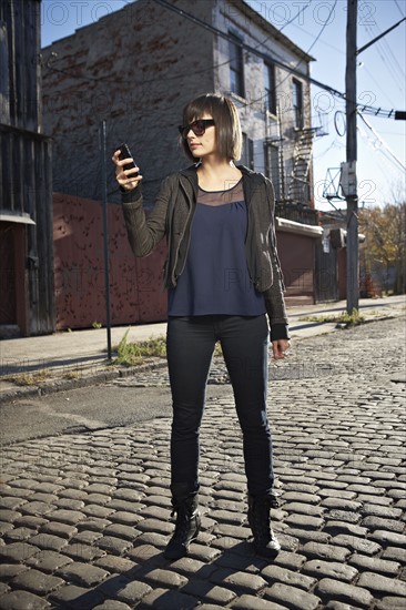 USA, New York City, Brooklyn, woman in street using phone. Photo : Shawn O'Connor