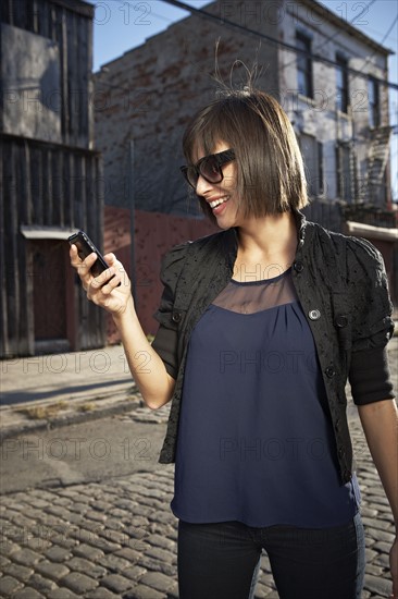 USA, New York City, Brooklyn, woman in street using phone. Photo : Shawn O'Connor