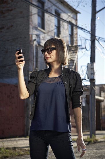 USA, New York City, Brooklyn, woman in street using phone. Photo : Shawn O'Connor