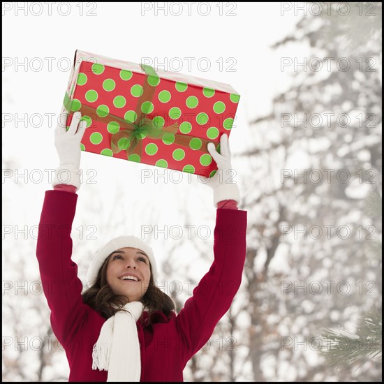 USA, Utah, Lehi, Young woman holding Christmas gift outdoors. Photo : Mike Kemp