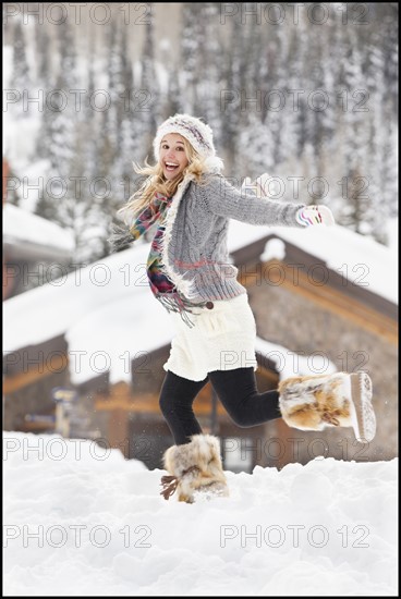 USA, Utah, Salt Lake City, young woman walking through snow in resort. Photo : Mike Kemp