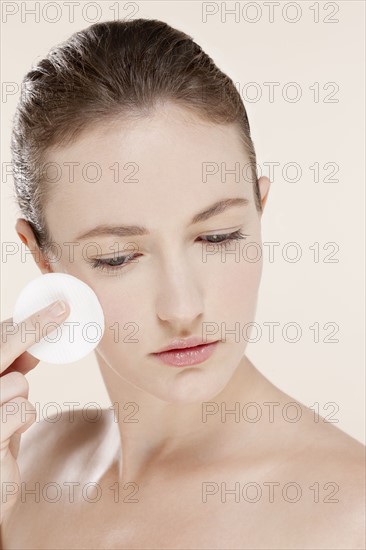 Portrait of young woman holding cotton pad. Photo : Jan Scherders