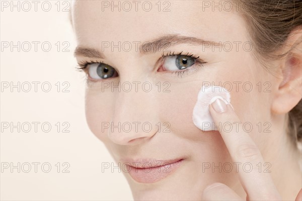 Portrait of young woman holding cotton pad. Photo : Jan Scherders