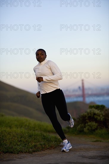 USA, California, San Francisco, Woman jogging, Golden Gate Bridge in background. Photo : Noah Clayton