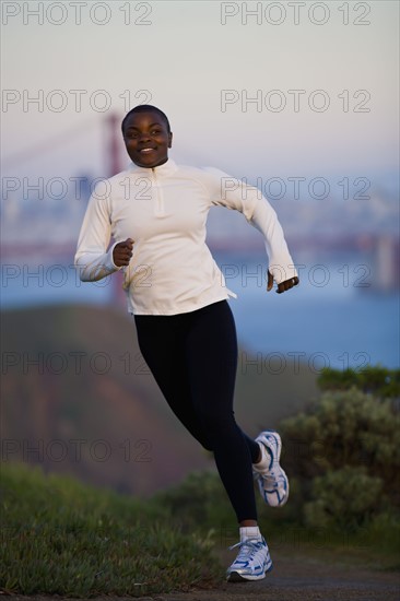 USA, California, San Francisco, Woman jogging, Golden Gate Bridge in background. Photo : Noah Clayton