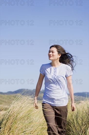 USA, California, Point Reyes, Young woman walking in grass. Photo : Noah Clayton