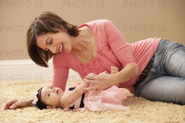 Woman with baby girl (2-5months) lying on floor. Photo : Mike Kemp