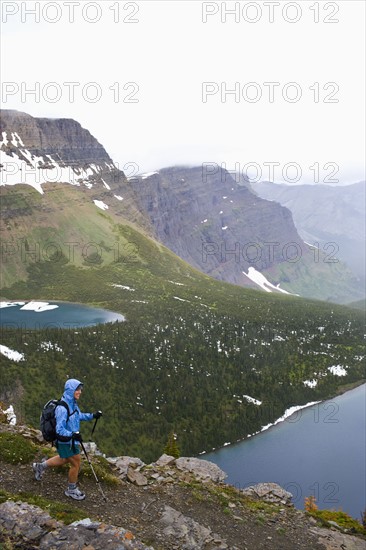 USA, Montana, Glacier National Park, Mid adult woman hiking with backpack during rain. Photo : Noah Clayton