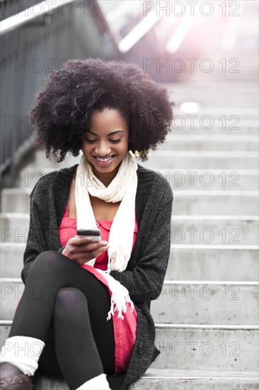USA, Washington State, Seattle, young woman sitting on steps and text messaging. Photo : Take A Pix Media