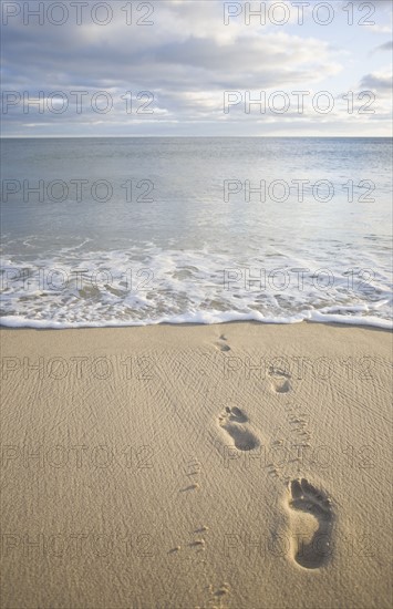 USA, Massachusetts, Cape Cod, footprints on beach at sunset. Photo : Chris Hackett