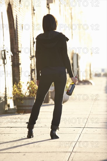 USA, New York City, Brooklyn, woman with bottle standing in street. Photo : Shawn O'Connor