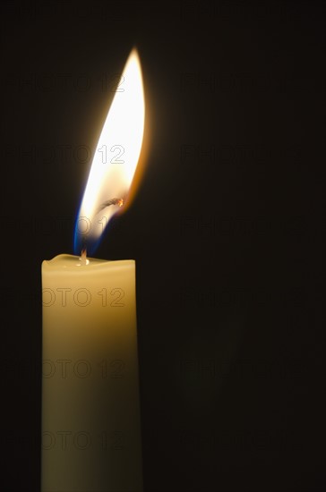 Lit candle on black background.