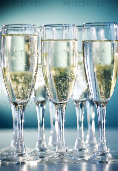 Close up of champagne flutes on blue background. Photo : Jamie Grill Photography