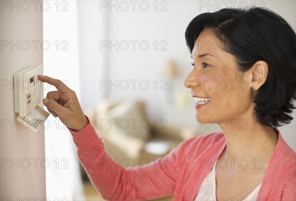 Mature woman adjusting room temperature.