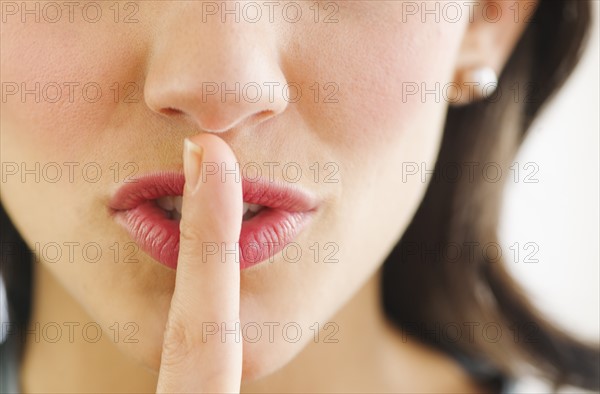 Young woman with finger on lips, close-up.