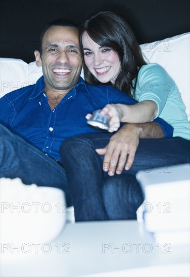 Couple watching television on sofa.