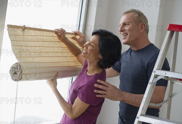Mature couple hanging blinds.