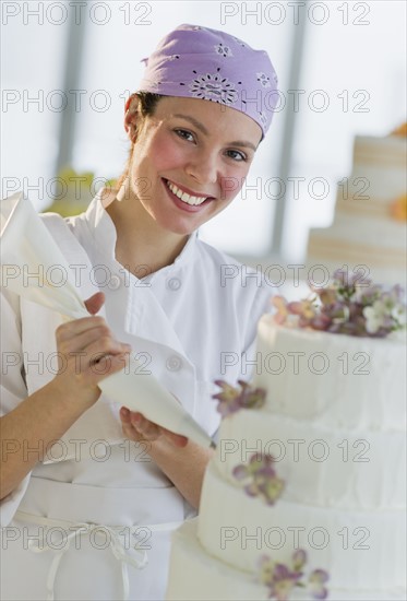 Portrait of happy young woman decorating wedding cake.