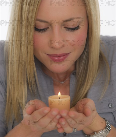 Young woman smelling scented candle. Photo : Daniel Grill