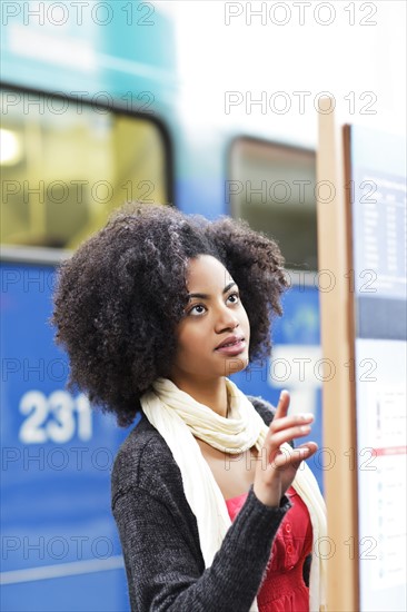 USA, Washington State, Seattle, young woman looking at arrival departure board. Photo : Take A Pix Media