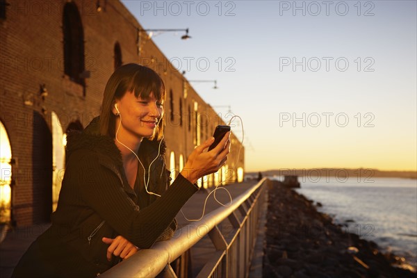 USA, New York City, Brooklyn, woman listening to mp3 player. Photo : Shawn O'Connor