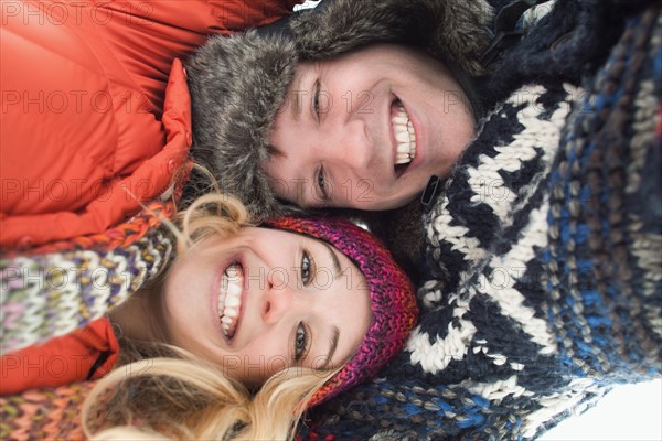 Portrait of young couple lying in snow. Photo : Mike Kemp