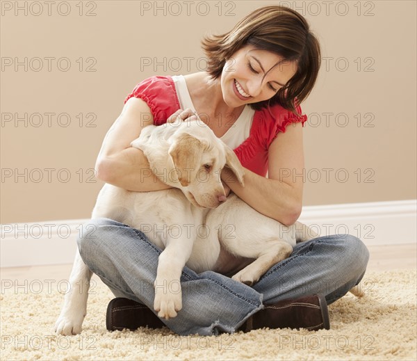 Woman embracing Labrador on carpet. Photo : Mike Kemp