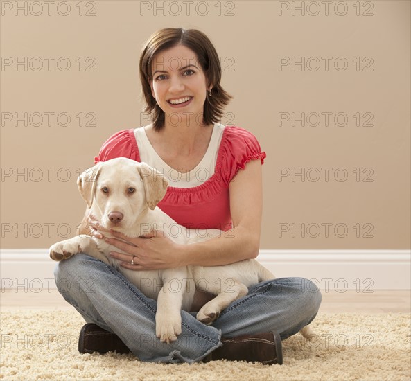 Portrait of woman embracing Labrador on carpet. Photo : Mike Kemp