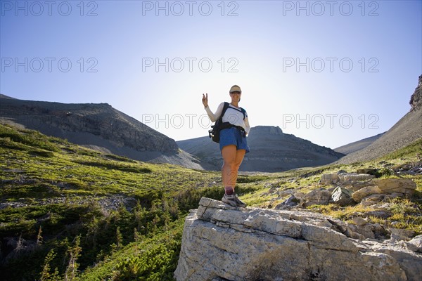 USA, Montana, Glacier National Park, Young woman posing with peace sign. Photo : Noah Clayton